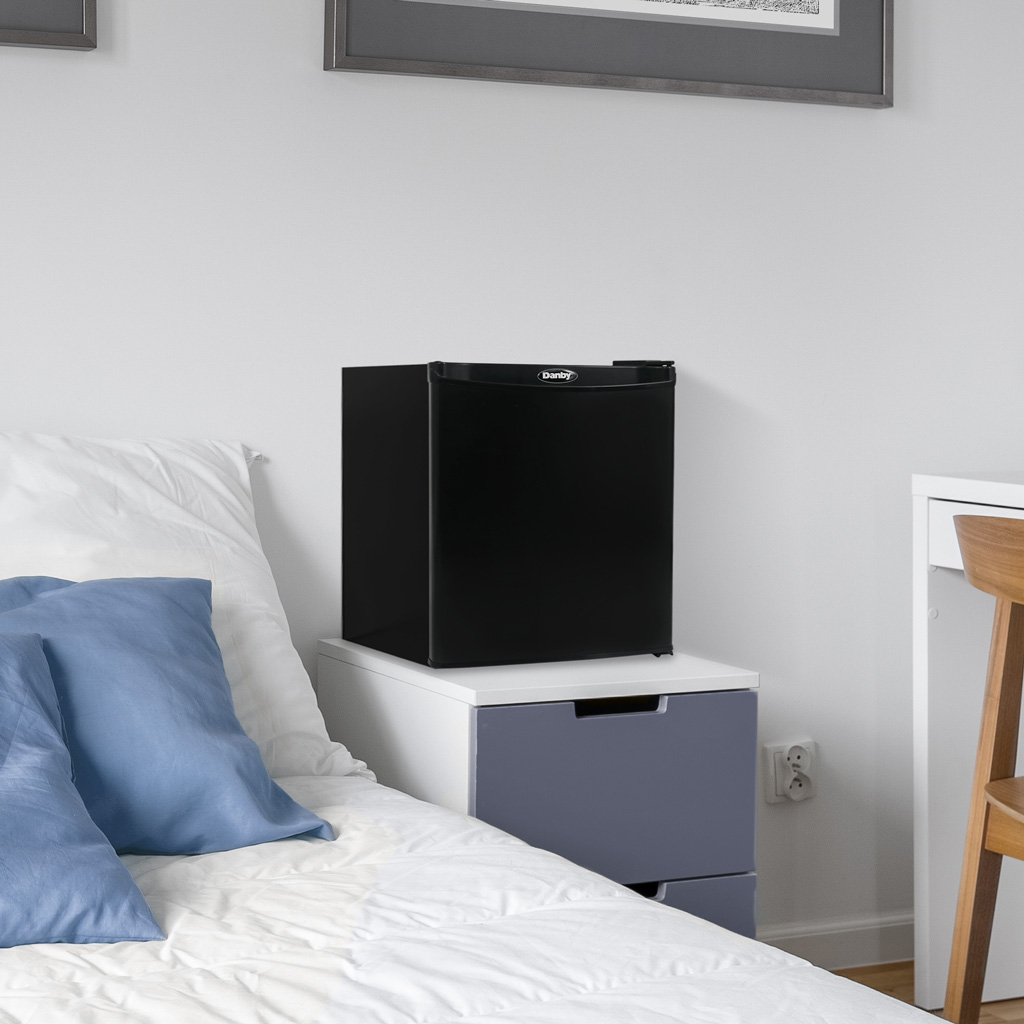 Danby DAR010A1BDB 1.0 cu ft compact fridge in bedroom setting with convenient beverage storage