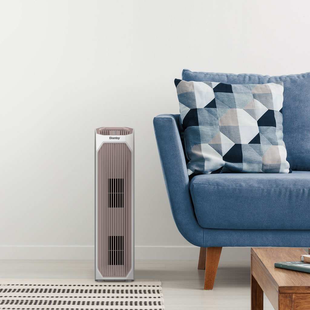 Danby appliances air purifier 210 sq ft DAP143BAW-UV in a living room setting beside a sofa and coffee table on a light floor