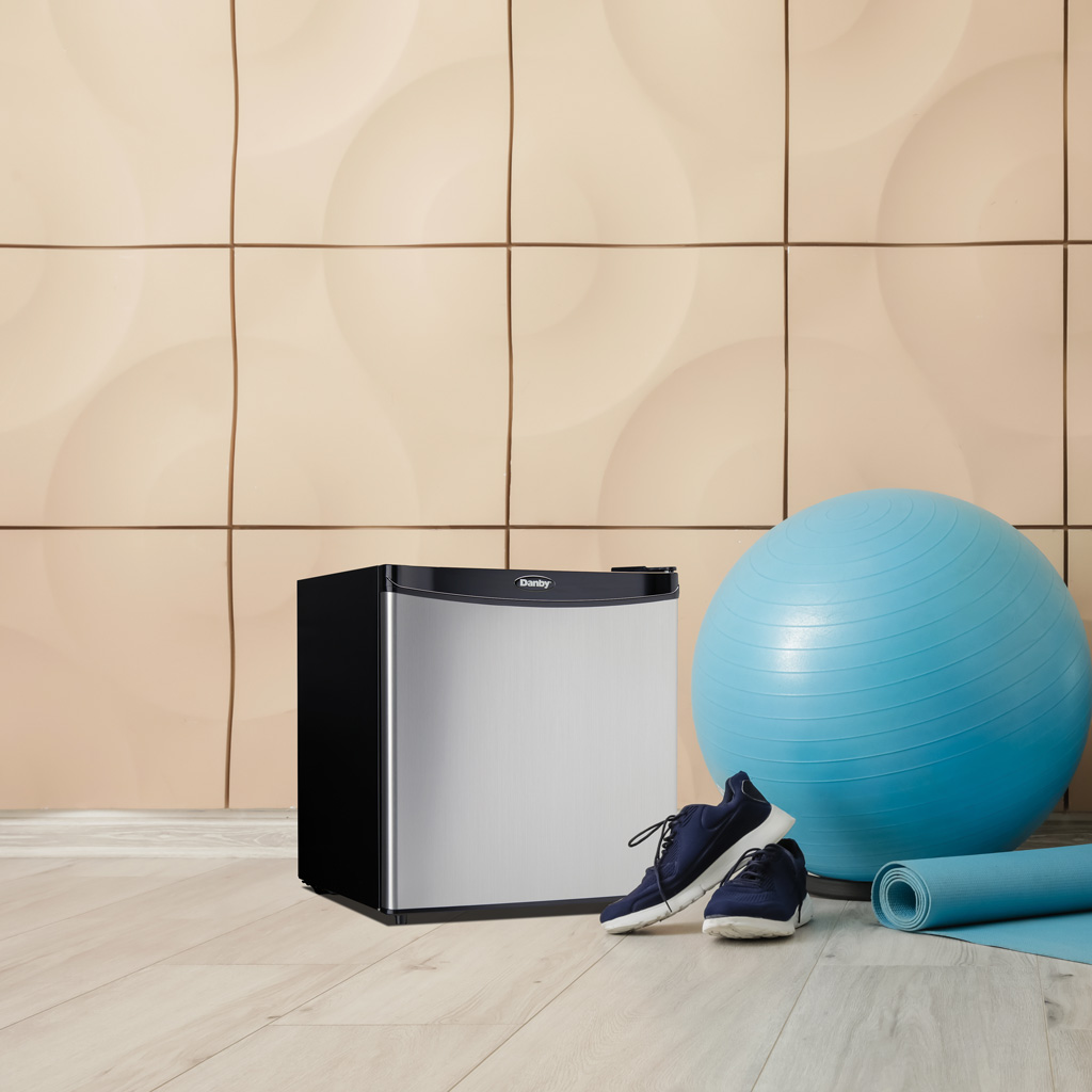 Danby 1.6 cu. ft. Compact Fridge in Stainless Steel Look 5 Danby appliances 1.6 cu ft compact fridge stainless DAR016A1BSS shown in a home workout space beside a yoga ball and shoes, highlighting compact placement and convenience