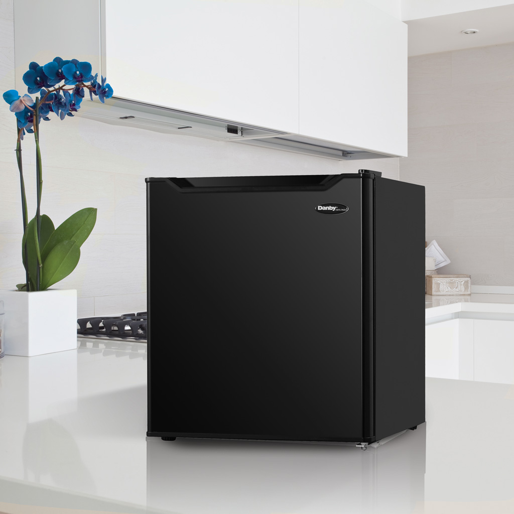 Danby appliances 1.6 cu ft compact fridge black DAR016A1BDB shown on a kitchen countertop beside cabinets and décor, highlighting compact placement and everyday use