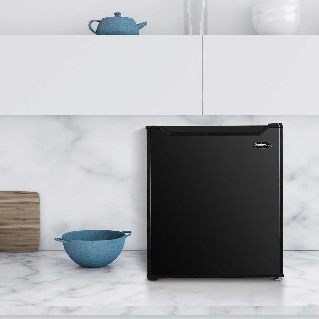 Danby appliances 1.6 cu ft compact fridge black DAR016A1BDB front view shown on a kitchen countertop beside dishes and décor, highlighting compact size and storage