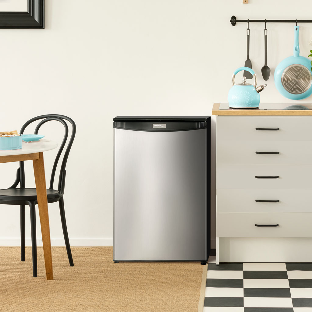 Danby appliances 4.4 cu ft compact fridge stainless DAR044A4BSSDD shown in a kitchen setting beside cabinets and sink highlighting compact under counter placement
