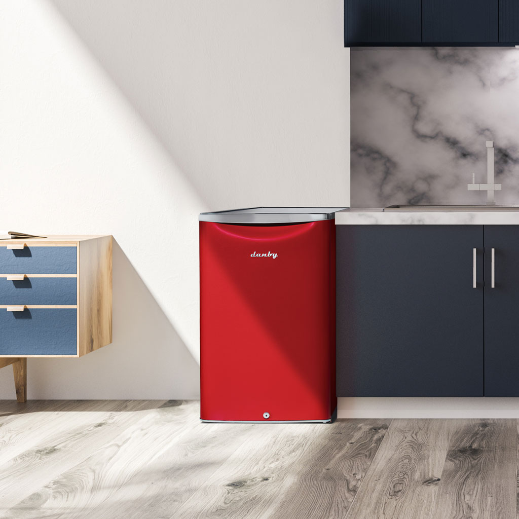 Danby appliances 4.4 cu ft compact fridge red DAR044A6LDB shown under a kitchen counter beside cabinets and backsplash highlighting compact placement and everyday use