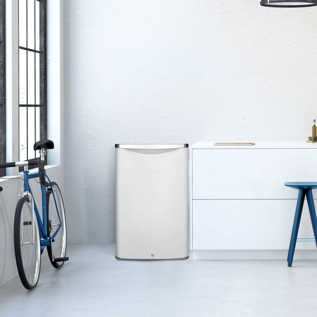 Danby 4.4 cu. ft. Contemporary Classic Compact Fridge in Pearl White 4 Danby appliances 4.4 cu ft compact fridge white DAR044A6PDB shown in a modern room beside a bicycle and white cabinetry highlighting compact placement and contemporary design