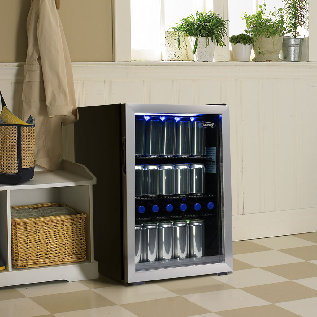 Danby 2.6 cu. ft. Free-Standing Beverage Center in Stainless Steel 5 Danby appliances 2.6 cu ft beverage center stainless DBC026A1BSSDB shown in a laundry room setting beside cabinets and countertop, displaying interior shelves stocked with beverage cans