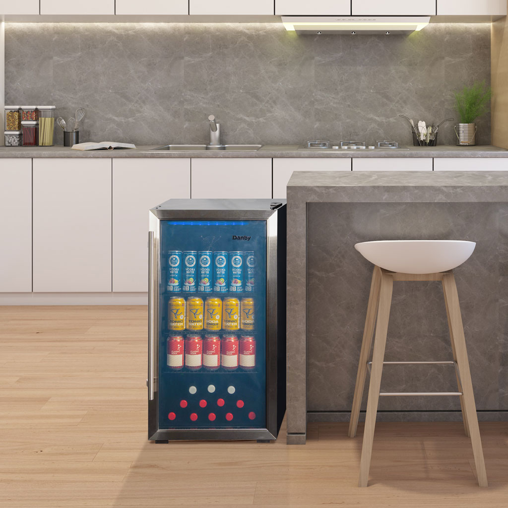 Danby 3.1 cu. ft. Free-Standing Beverage Center in Stainless Steel 4 Danby appliances 3.1 cu ft beverage center stainless DBC117A2BSSDD-6 shown in a kitchen setting beside a counter and stool with beverage cans visible through glass door
