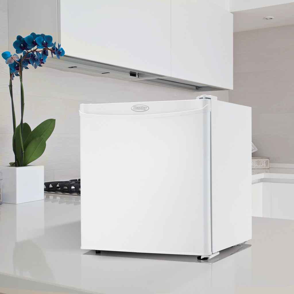 Danby appliances 1.6 cu ft compact fridge white DCR016A3WDB shown on a kitchen countertop beside cabinets and wall surfaces highlighting compact placement and everyday use