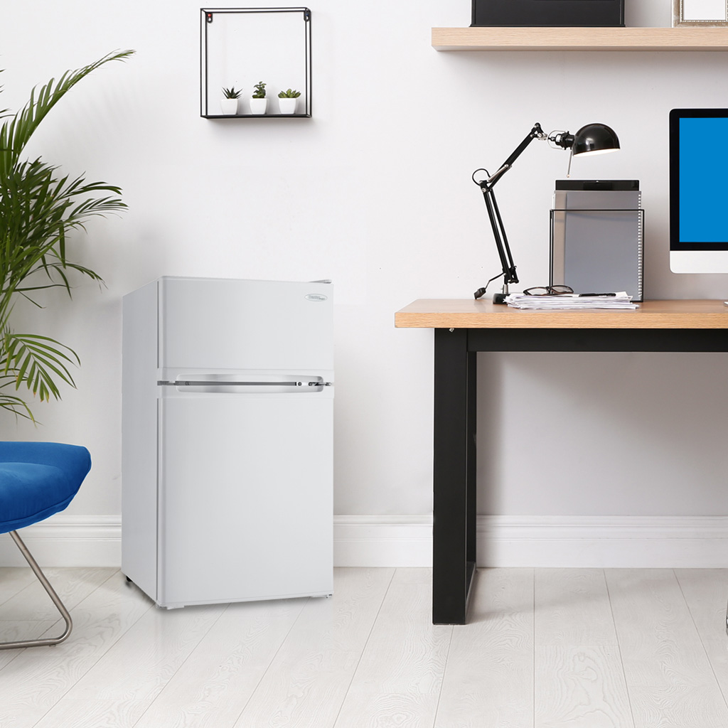 Danby appliances 1.6 cu ft compact fridge white DCR016A3WDB shown beside a desk in a home office setting with shelving, lamp, and computer highlighting compact placement and everyday use