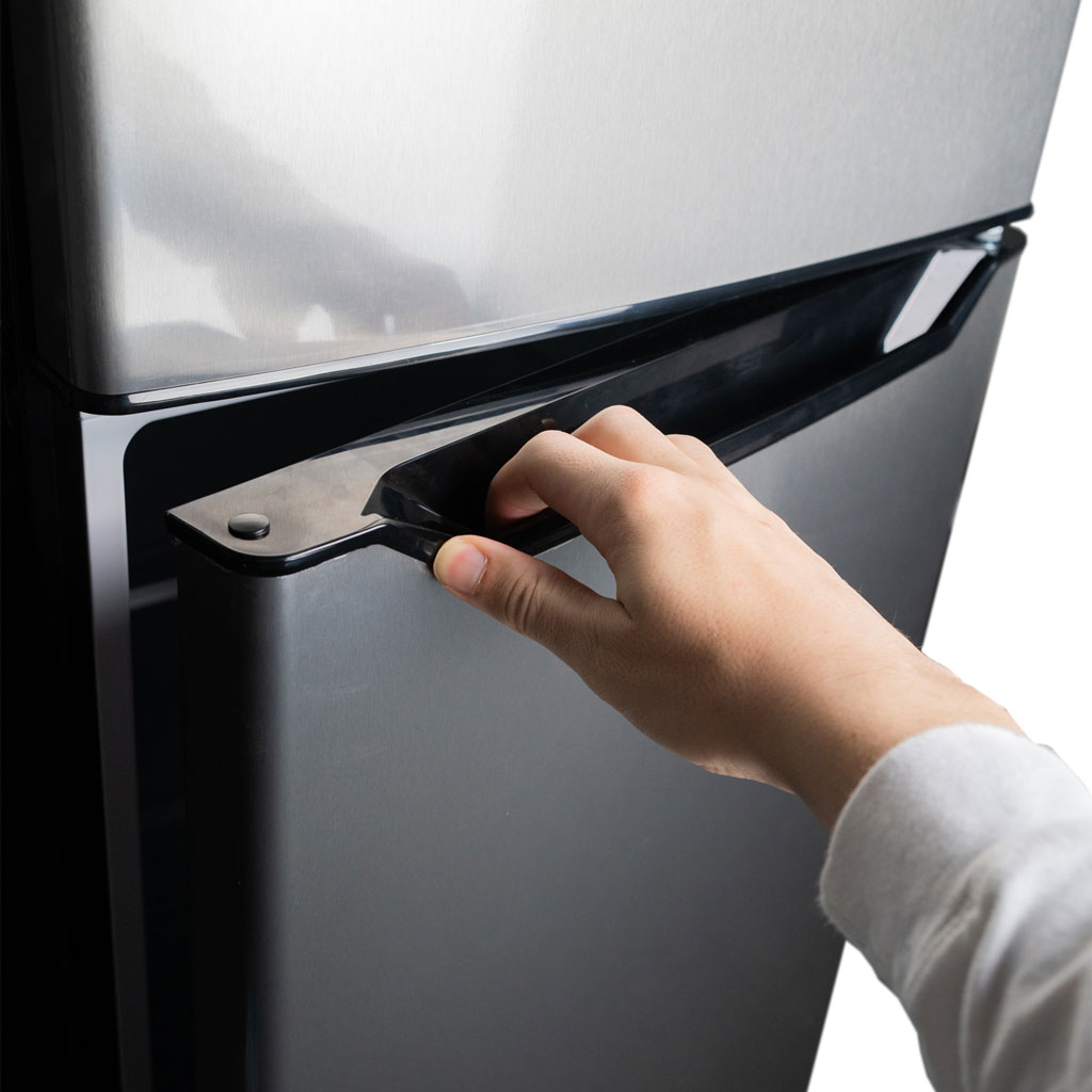 Danby appliances 4.5 cu ft compact fridge stainless DCR045B1SLDB 2 door close‑up of hand opening upper freezer door with integrated handle on stainless finish