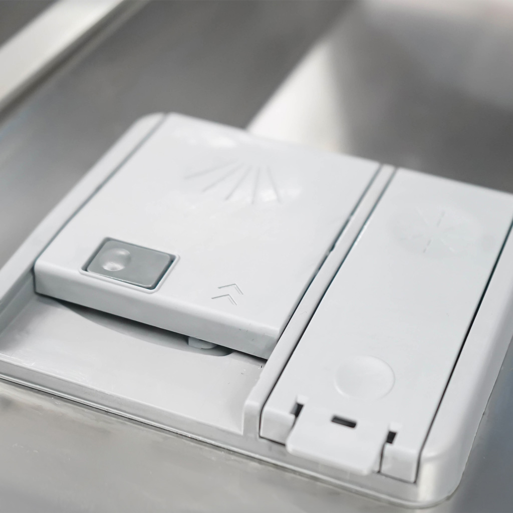 Danby appliances 18 inch built in dishwasher white DDW18D1EW detergent dispenser compartment with rinse aid lid shown in a close-up view inside the dishwasher door