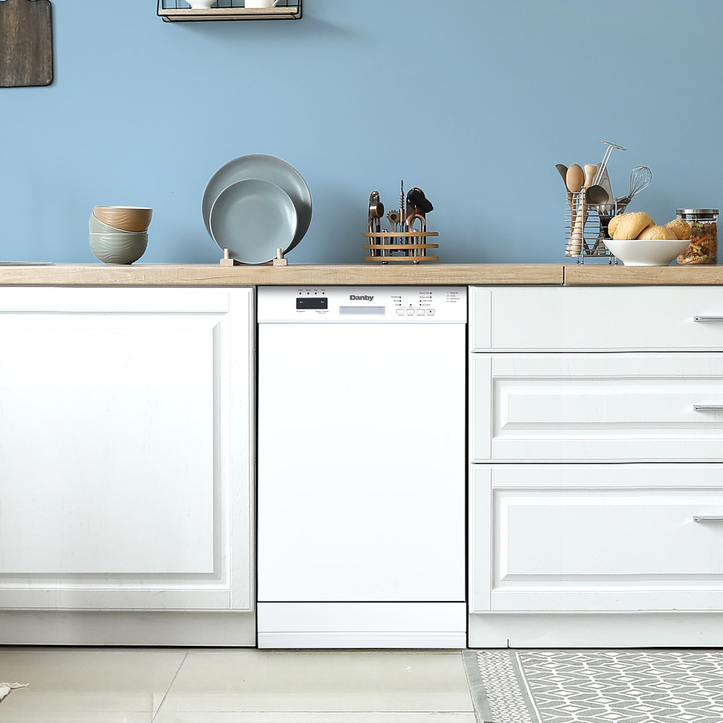 Danby appliances 18 inch built in dishwasher white DDW18D1EW installed in a modern kitchen with white cabinetry and wooden countertop shown in a front view