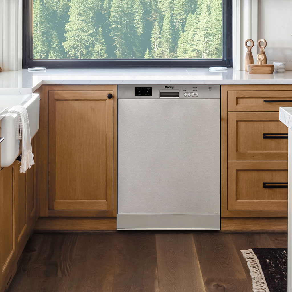 Danby appliances 24 inch built in dishwasher DDW2400ESS installed in kitchen with wood cabinets and white countertop in a clean front view