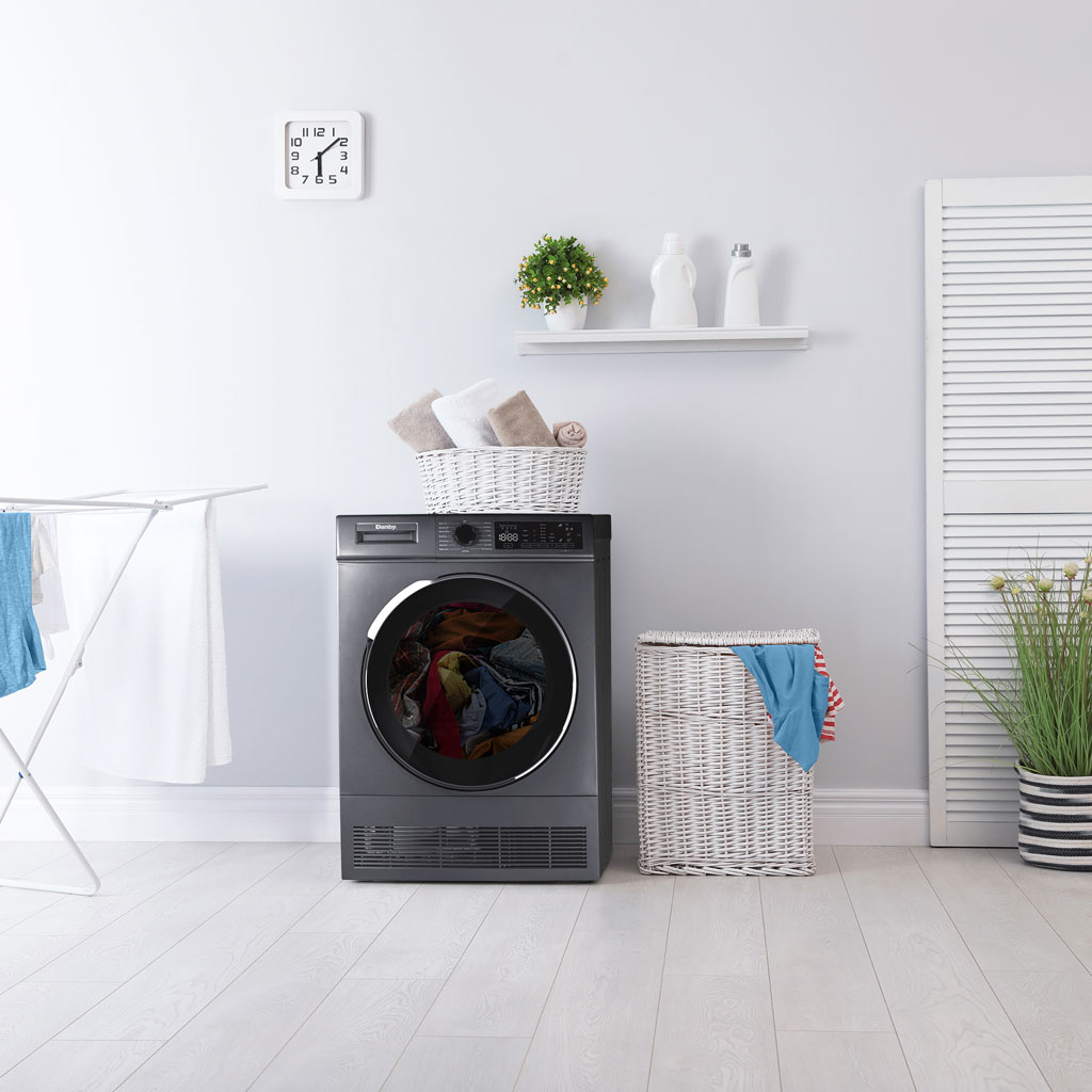 Danby DDY040D1DSDB 24 inch compact condensing dryer in modern laundry room setting beside woven baskets and drying rack with light decor