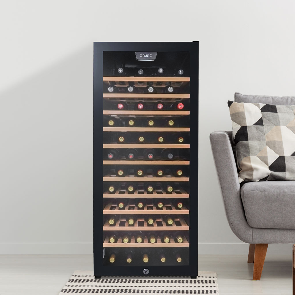 Danby 94 Bottle Free-Standing Wine Cooler in Black 4 Danby appliances 94 bottle wine cooler black DWC094L1B shown in a living room setting beside a sofa and side table with wooden shelves stocked with wine bottles visible through glass door