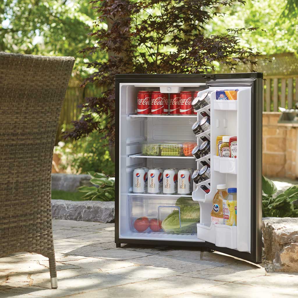 Danby DAR044A6BSLDBO 4.4 cu ft outdoor fridge with door open displaying beverages in outdoor setting