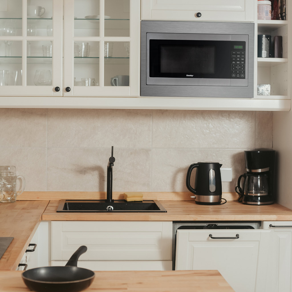 Danby DMW16A1SSDB 1.6 cu ft countertop microwave on kitchen countertop in modern kitchen setting