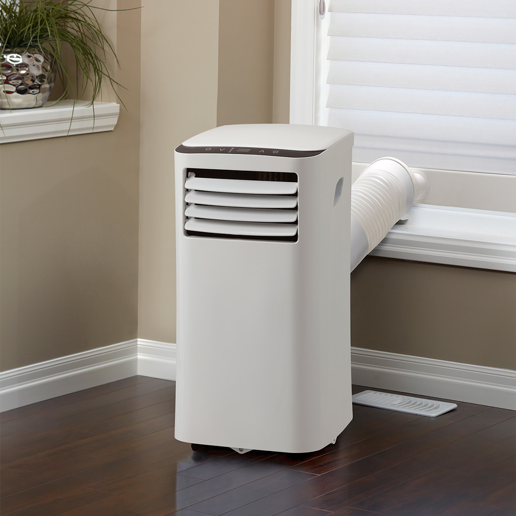 9000 BTU air conditioner White portable unit installed with window hose cooling room