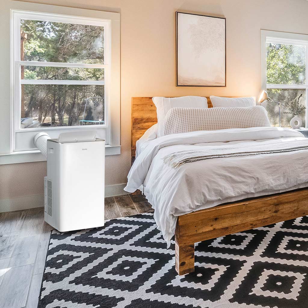 Danby DPA080B2WDB 12000 BTU air conditioner vented through window cooling a bedroom beside bed