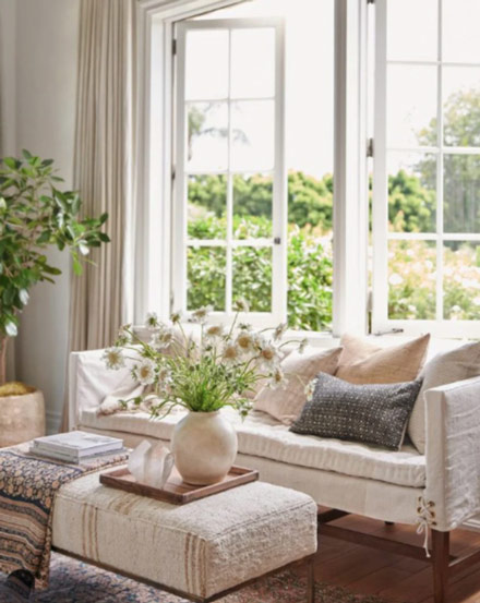 Bright living room with open windows and natural light featured in a spring refresh guide for a more comfortable and energy-efficient home