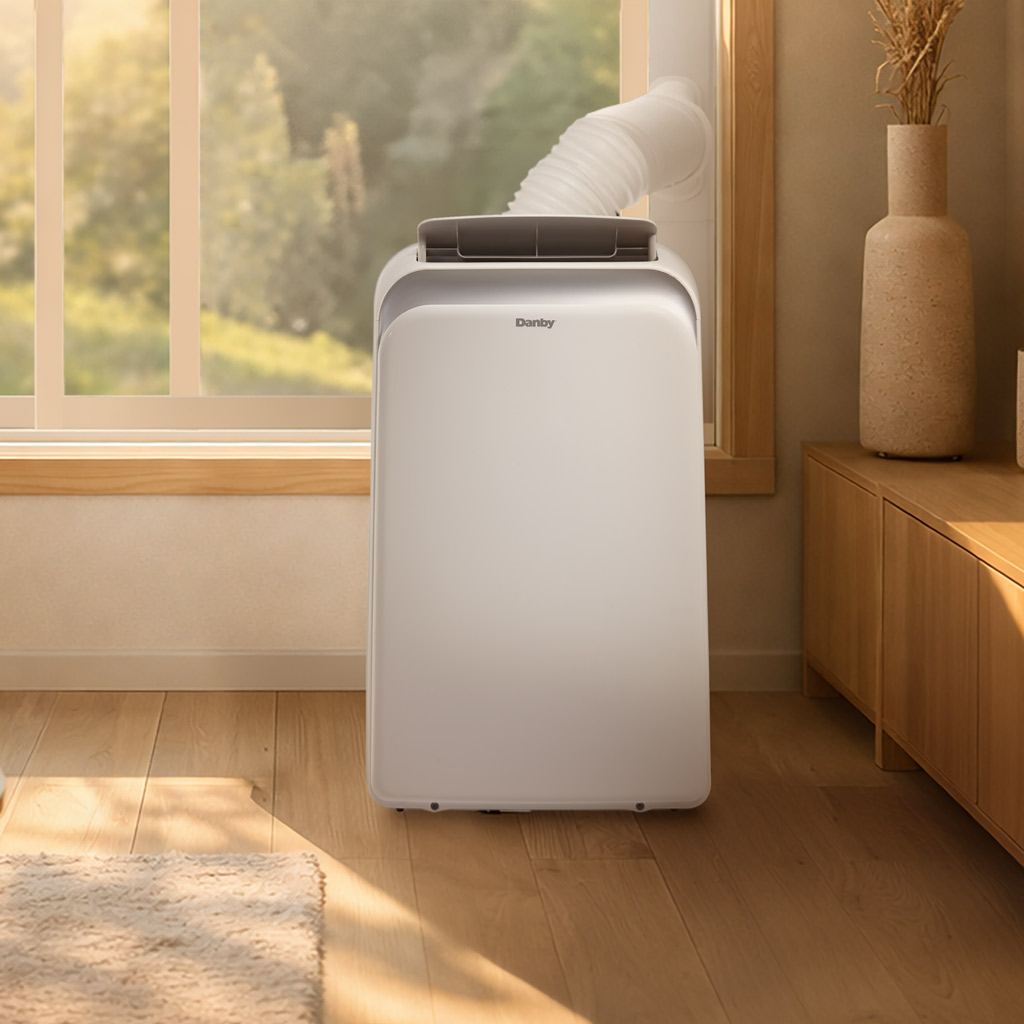 Danby DPA060B1WDB 10000 BTU air conditioner vented through window cooling room beside cabinet