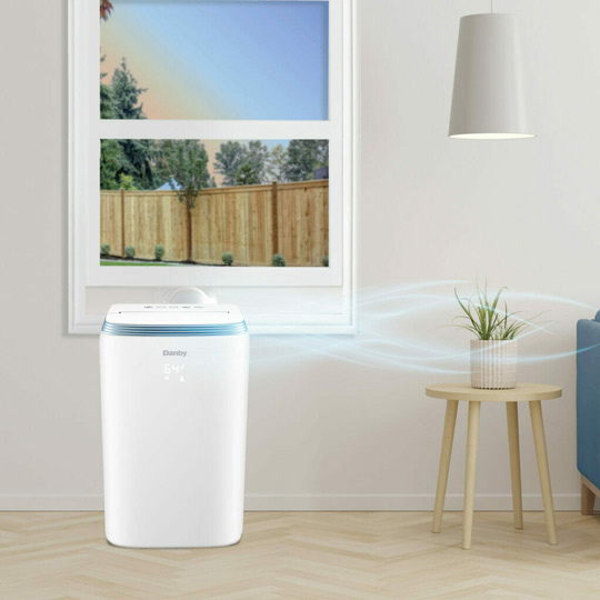 Portable air conditioner beside window illustrating how to use your AC as dehumidifier