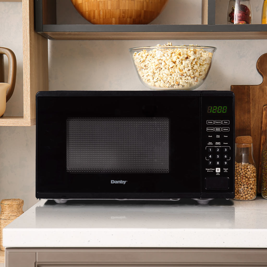 Danby DMW091A1B 0.9 cu ft countertop microwave in kitchen setting on countertop with cabinetry