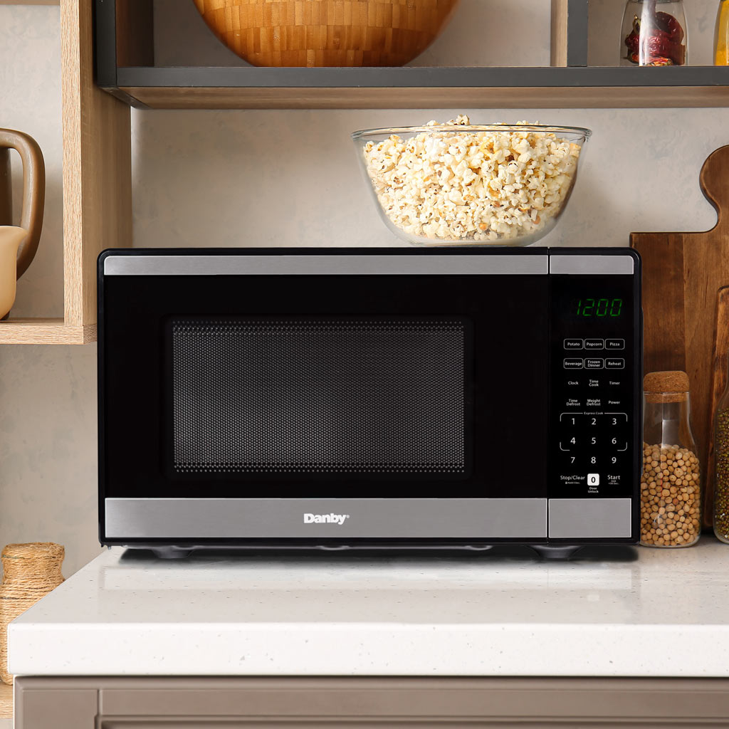 Danby DMW091A1SS 0.9 cu ft countertop microwave in kitchen setting on countertop with cabinetry
